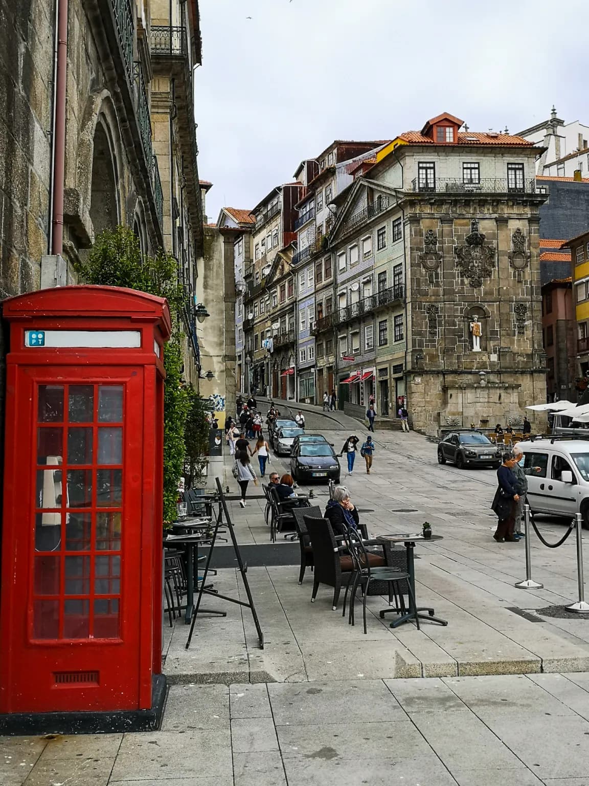 Picture of a street in Porto with a street side cafe and red european style phone booth.