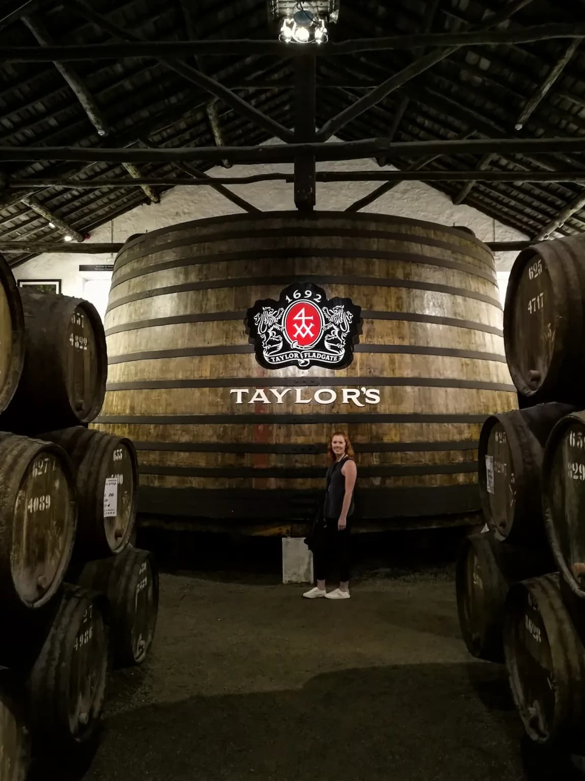 Picture of giant wine cask with the company label surrounded by smaller barrels of wine.